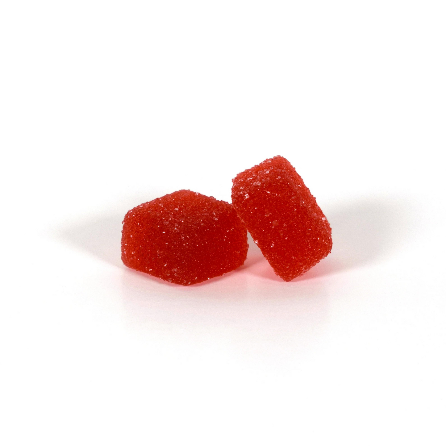 Two red, sugar-coated Strawberry Watermelon Broad Spectrum Gummies by Jolly Cannabis (0mg THC, 50mg CBD) rest on a white surface—one upright, one flat—showcasing their textured finish. The background is plain and uncluttered.